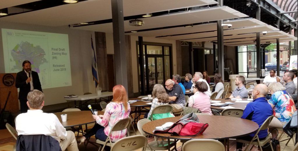 Owen Kerney answers questions about the ReZone Syracuse plan and map for participants in the atrium at City Hall Commons.